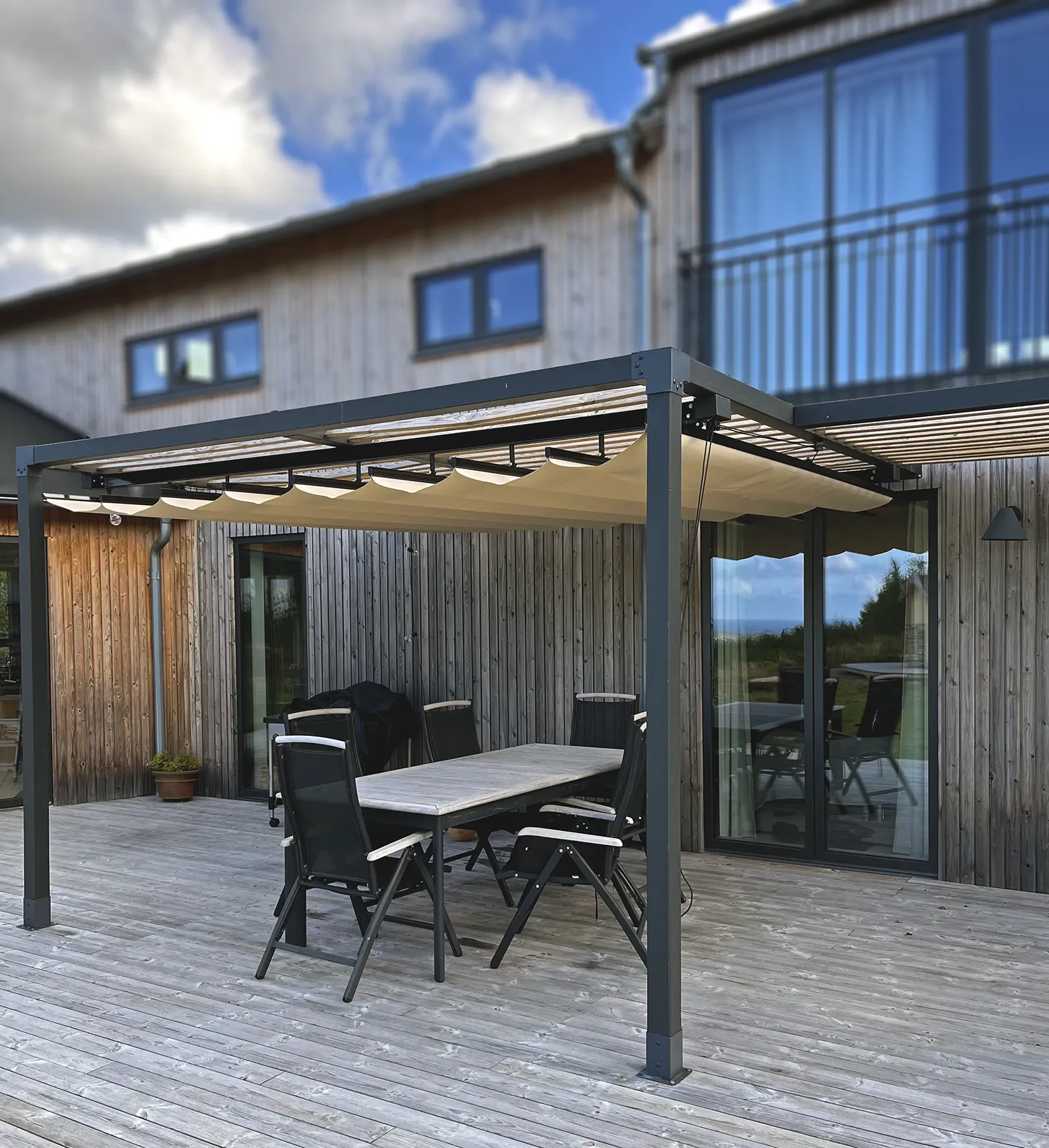 Pergolamarkis till pergola Svart pergola med beige pergolamarkis på altan