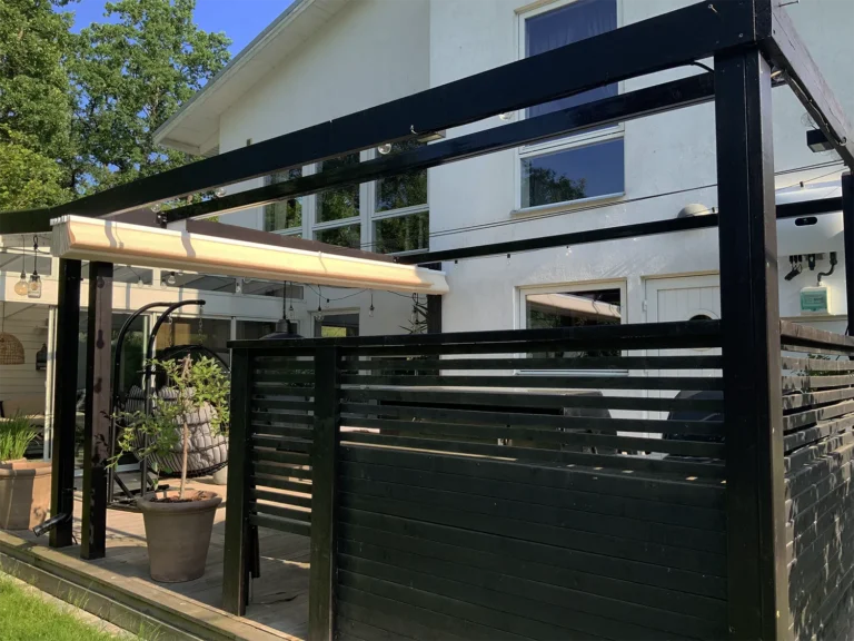 Beige pergolamarkis samlad vid ena sidan av en svart pergola