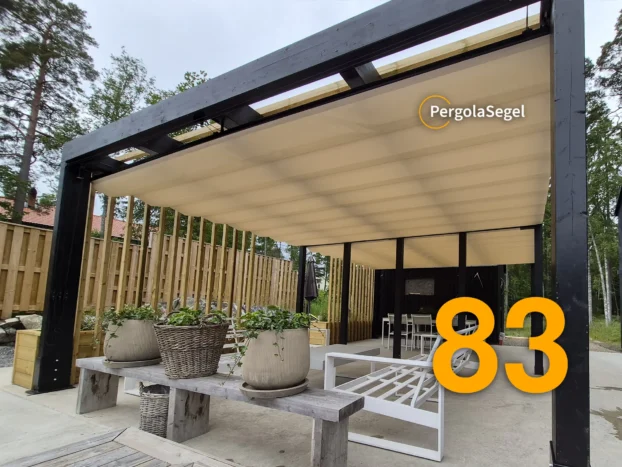 Beige pergolasegel utdraget över uteplats med vita loungemöbler och planteringar