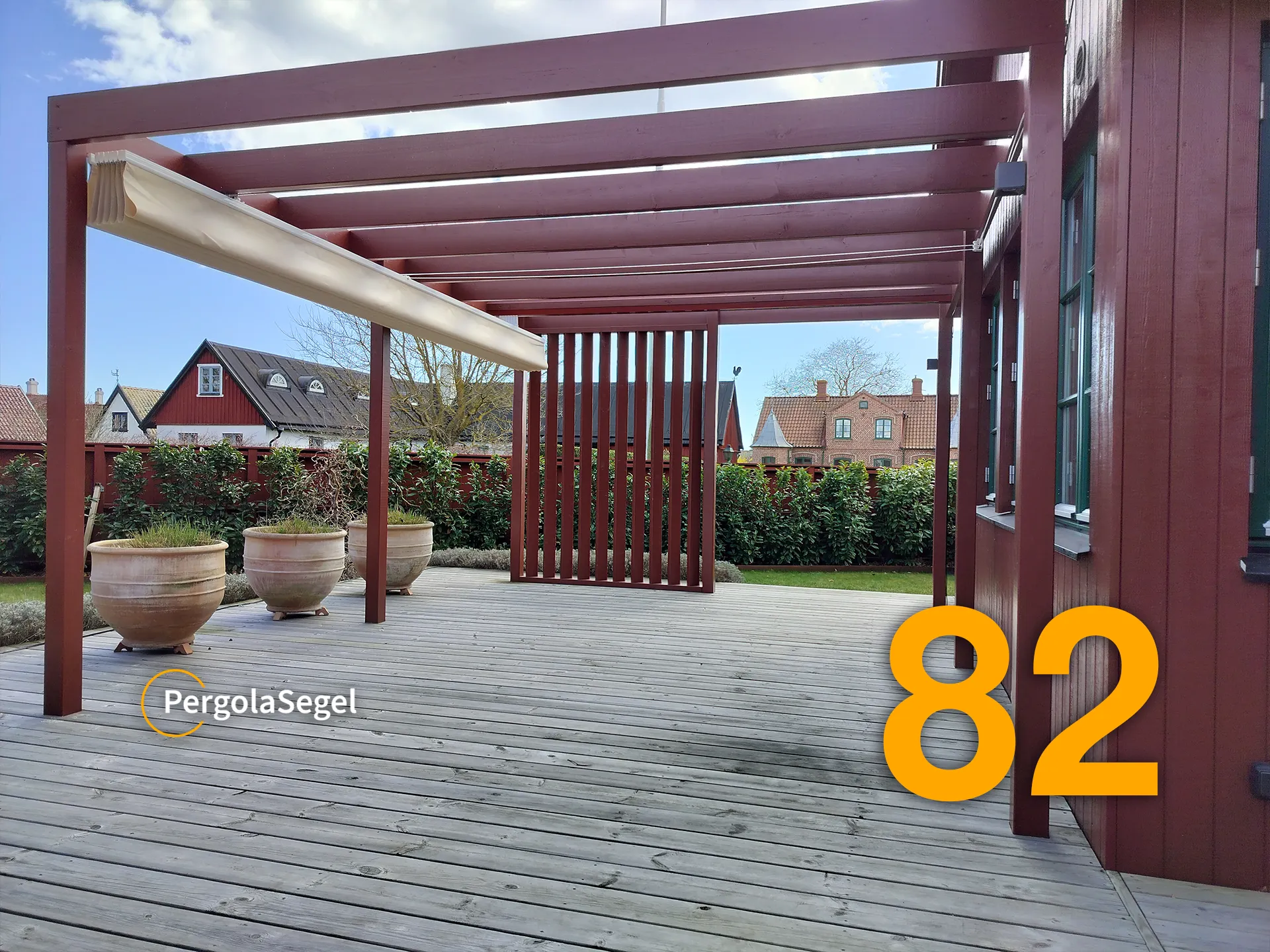 Faluröd pergola i Åhus med beige segel insamlat längst från huset så att fönstren hålls fria