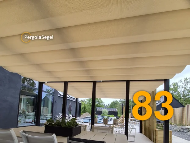 Matplats under utdraget beige pergolasegel intill husets glasfasad
