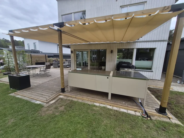 Pergola med beige duk som öppnas från båda sidor och möts i mitten över uteköket