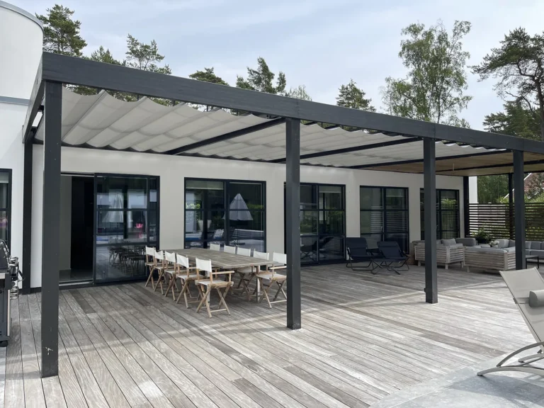 Stor svart träpergola med ljusgrå pergolamarkiser med sidoöppning över matplats och lounge