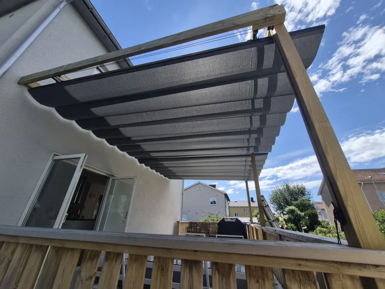 Undersida av grå pergolamarkis med mittöppning monterad på en träpergola vid huset