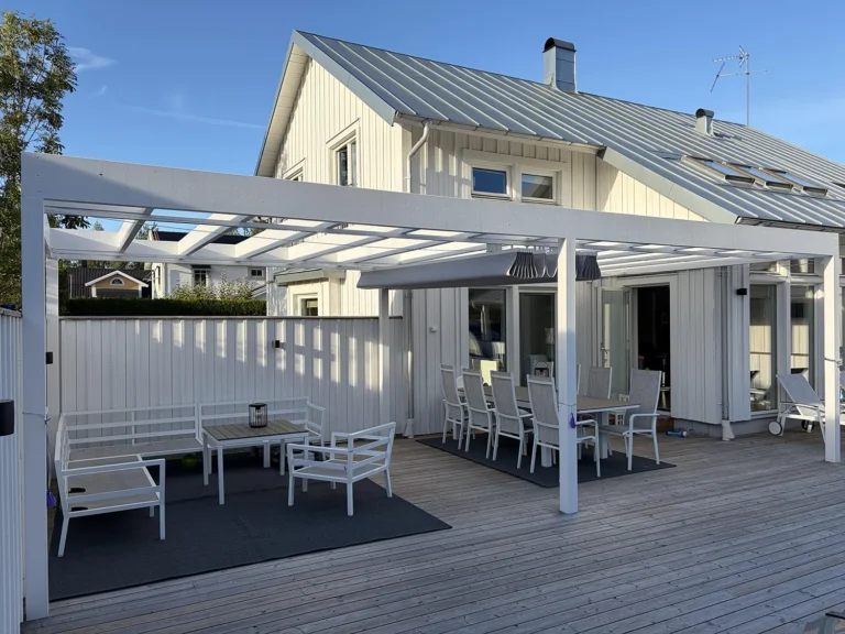 Vit pergola med grå pergolamarkis med mittöppning över en möblerad träaltan